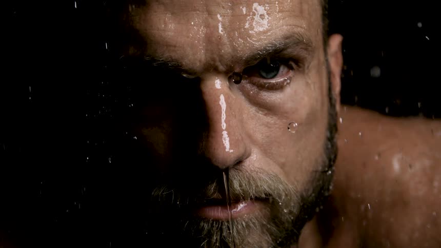Close up of a man looking fierce with water showering over him