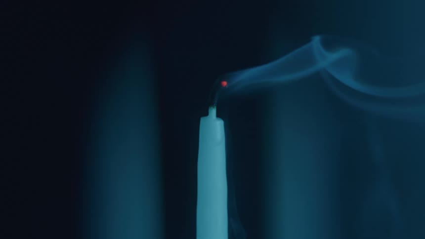 A candle being blown out at night