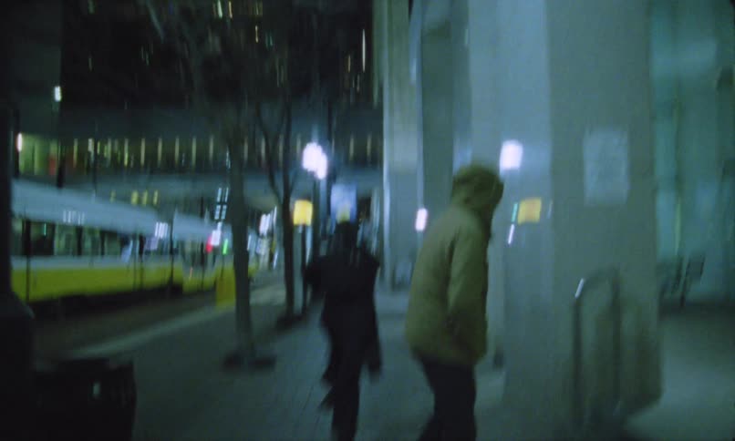 A man running on the sidewalk bumps into another man wearing a jacket as a metro train is about to depart