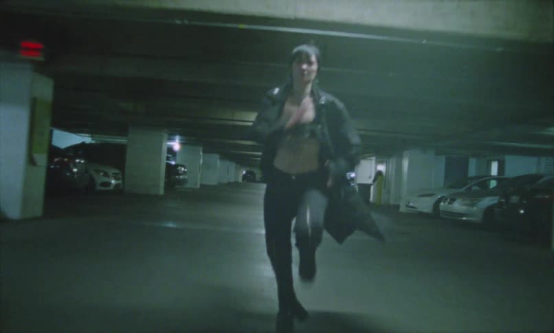 Woman runs in an underground parking lot under dim artificial light