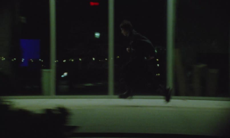 A young man and a young woman running on the sidewalk along the city streets