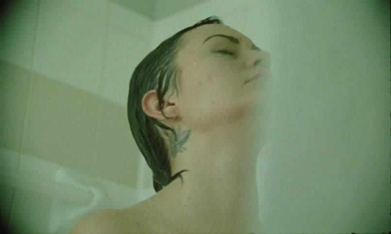 Woman with wet hair tilting her head back while showering