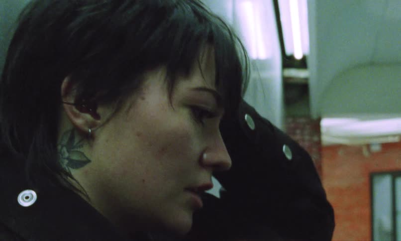 Woman with a neck tattoo looking to the side in an urban setting