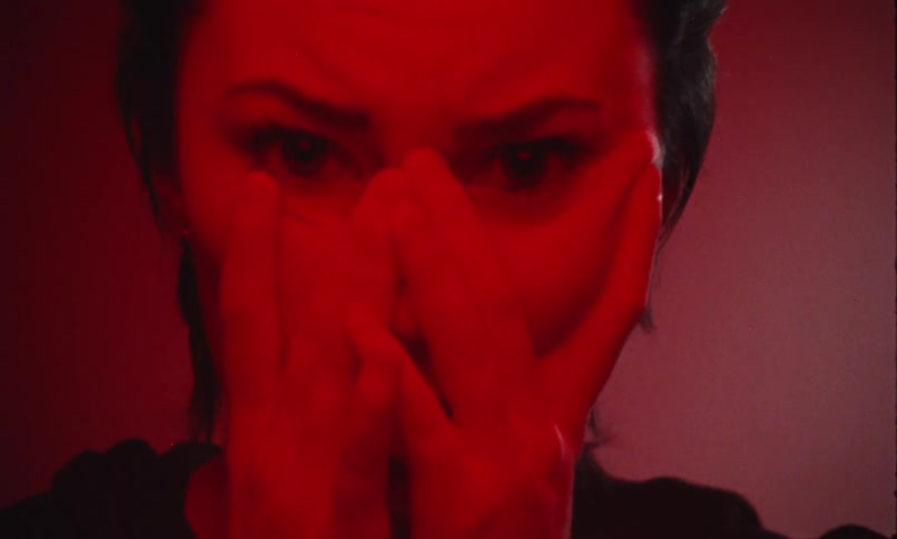 Close up portrait of a young anxious woman in a red lit room