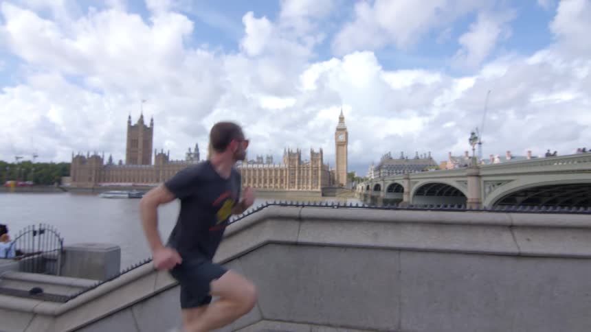 Man runs along the river thames with the british parliament in the background