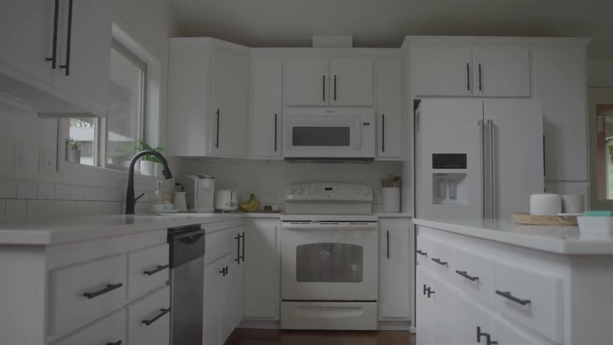 A home kitchen contains white cabinetry and white appliances