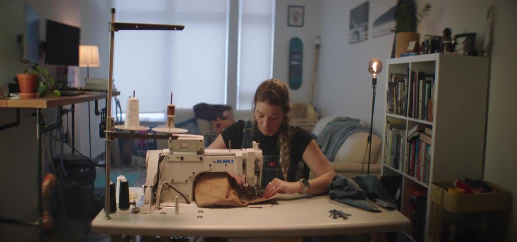 Woman sews fabric on an industrial machine inside a home studio