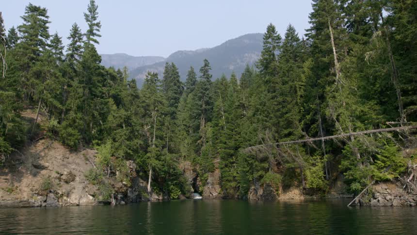 A view of a lake or pond surrounded by trees and cliffs