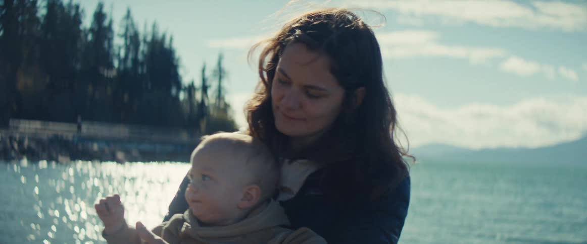The mother is holding her baby on the beach