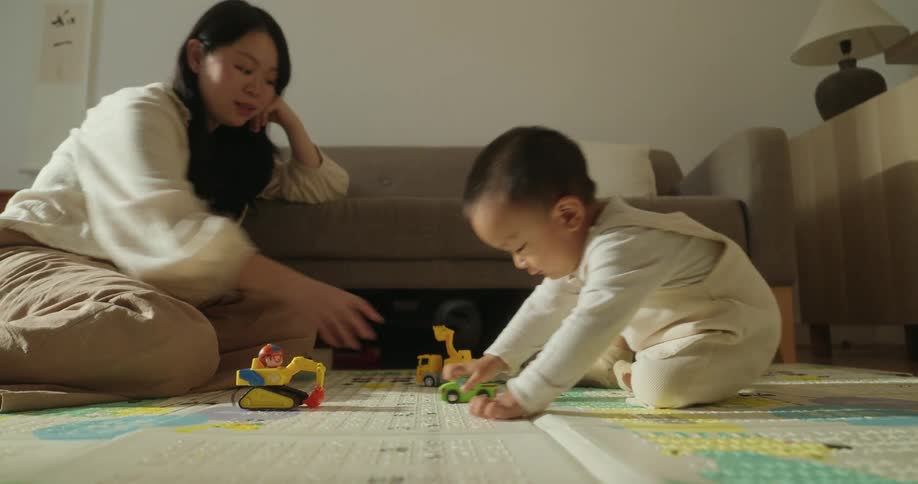 Mother and son play with toy cars on the floor in a cozy living room