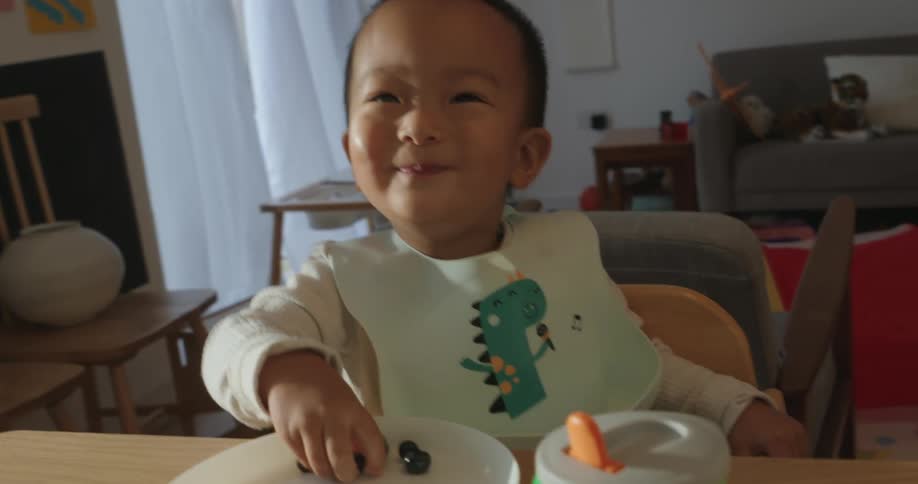 Child smiling while eating blueberries at home