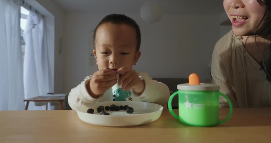 Child eats fruit next to her mother