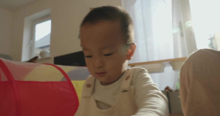 A child sitting on the living room floor playing with toys at midday