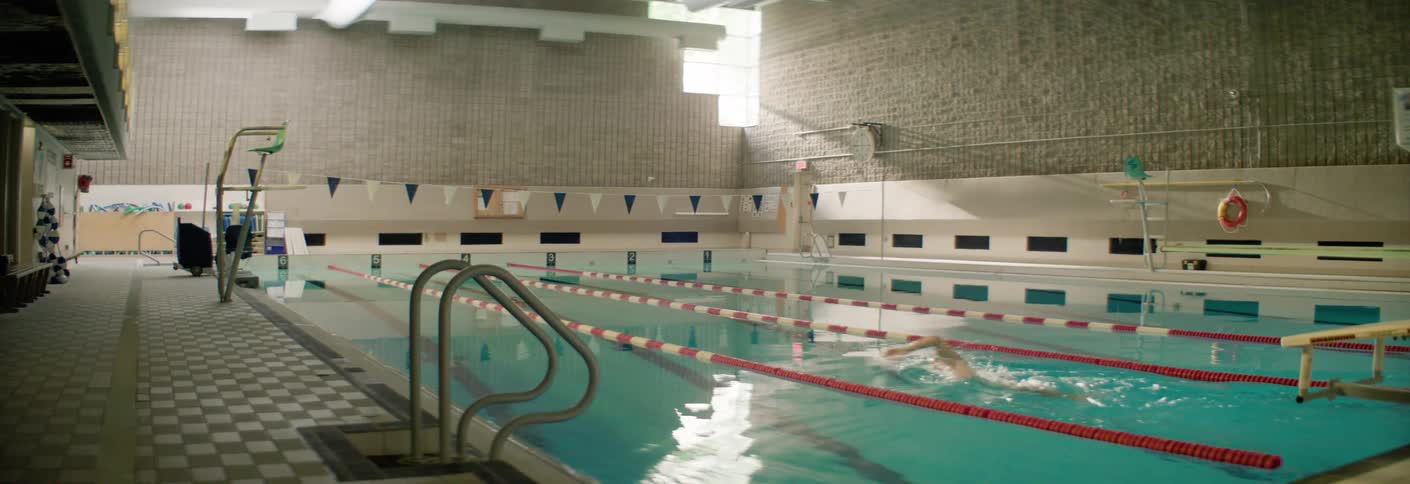A swimmer trains in an indoor pool under soft daylight