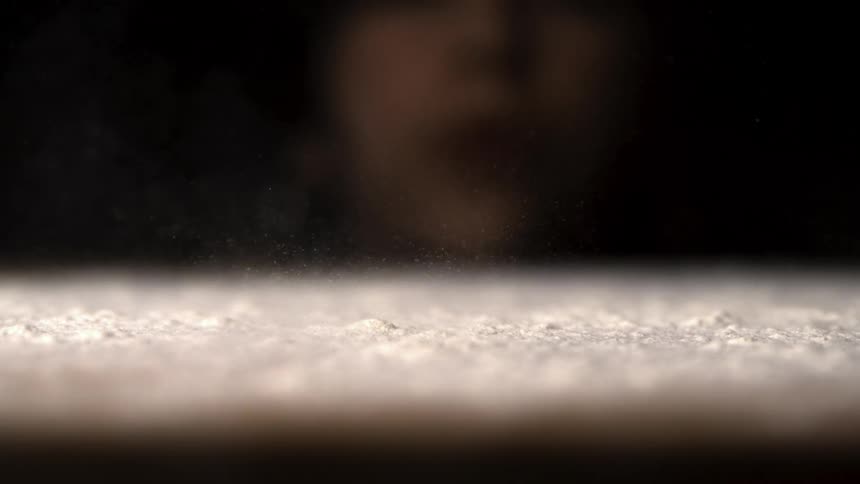 Person blowing on a dustcovered surface