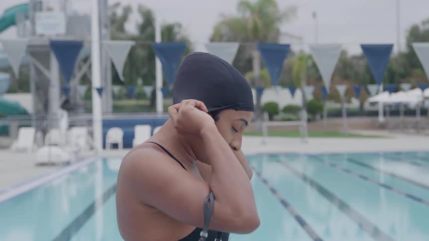 Swimmer adjusts her swim cap at the edge of the pool
