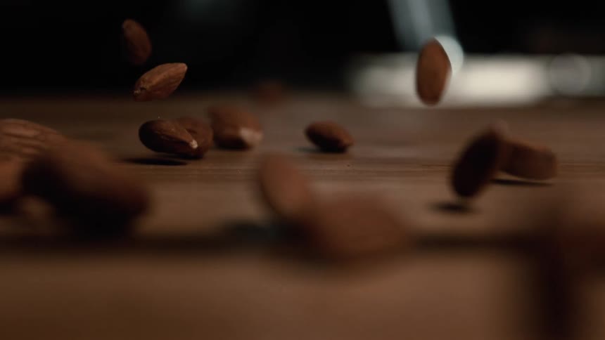 A handful of almonds scattered on a wooden surface at midday