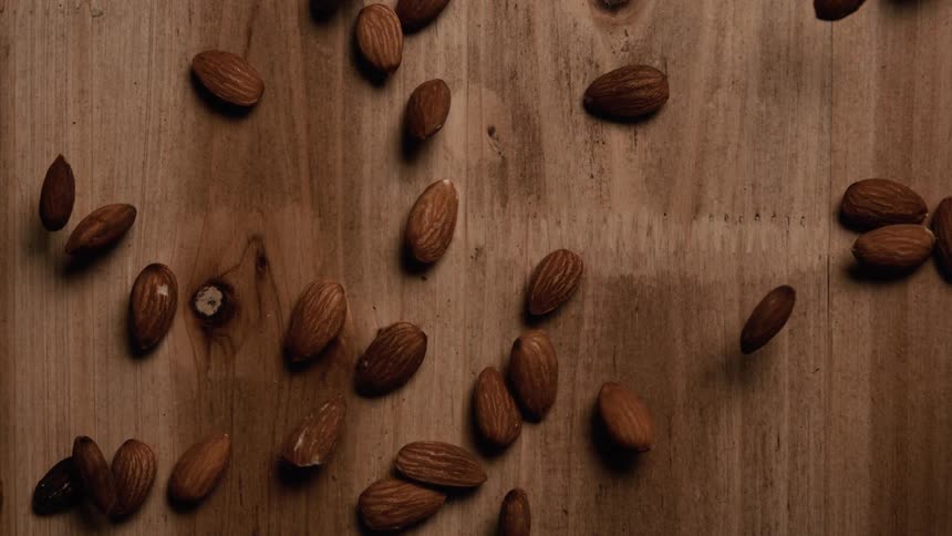 A closeup of scattered almonds resting on a wooden surface