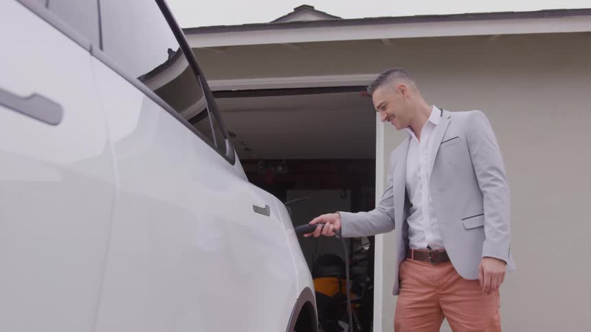 A man is plugging a charger into an electric car