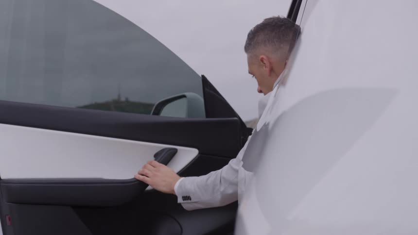 A man wearing formal clothes getting out of a car