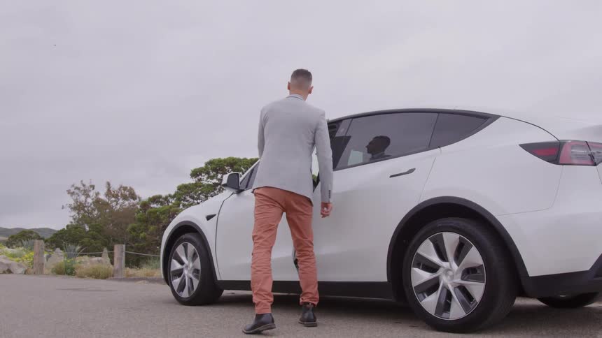 A man wearing formal clothes getting into a car