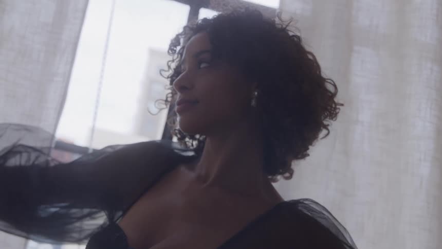 Close up portrait of a young woman standing by the window indoors during daytime