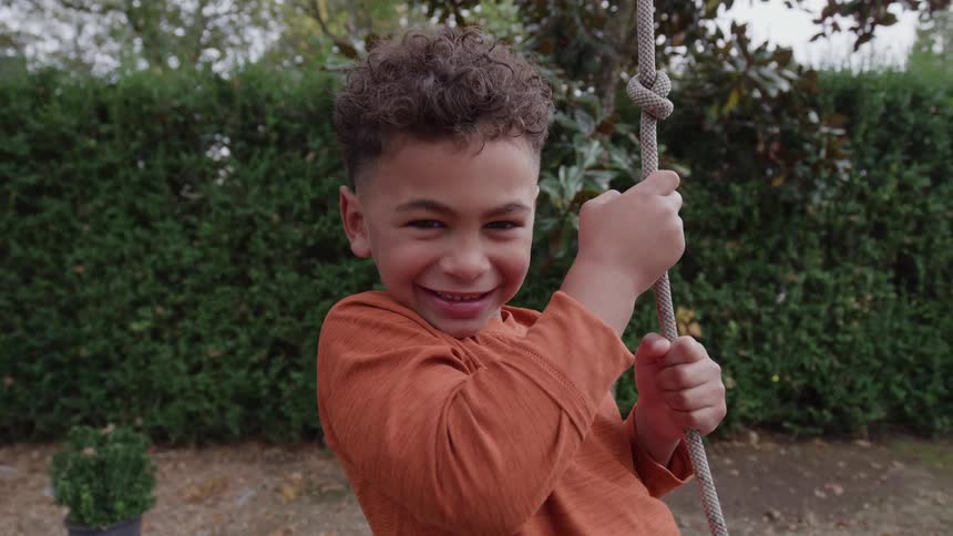 A portrait of a boy on a swing on a sunny day