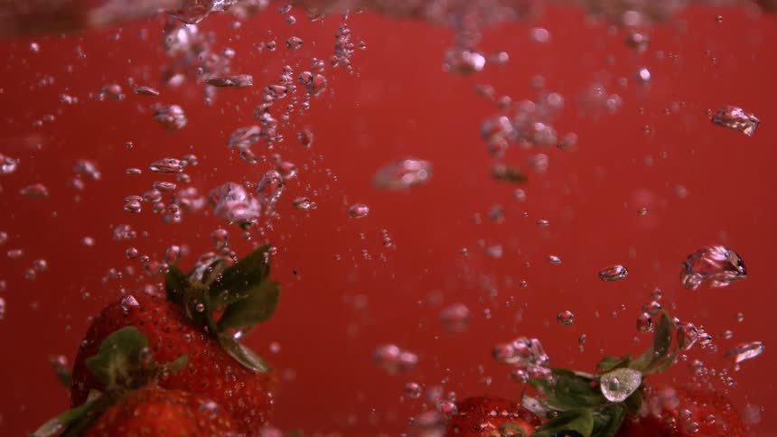 Strawberries are dropped into a beverage