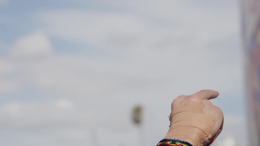Person waving their hands in the air on a cloudy day