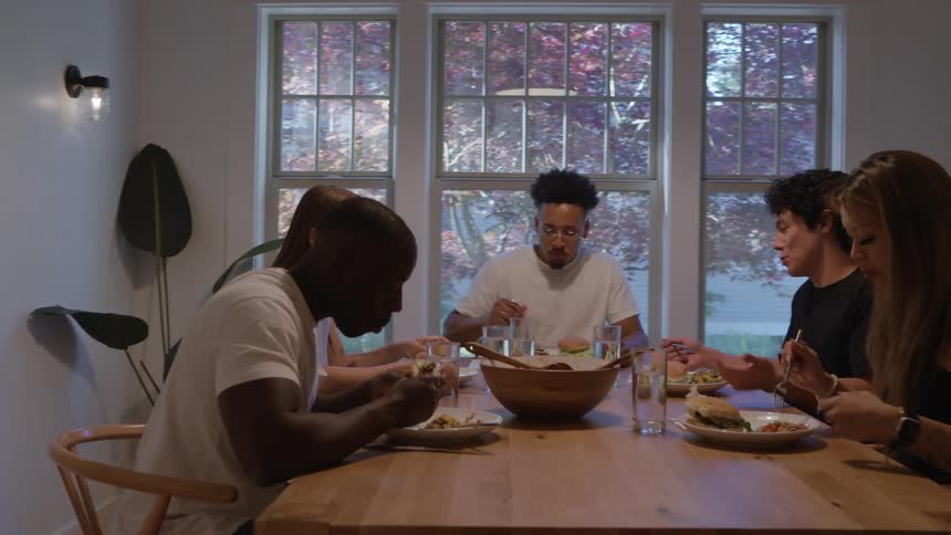 Group of friends share a meal together around a wooden table