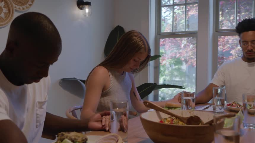 People hold hands and say a prayer before the meal