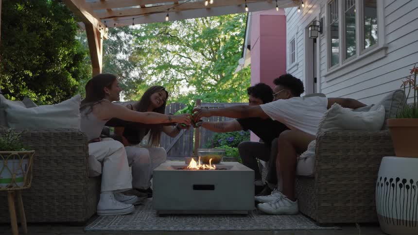 A group of people drinking together by a fire pit