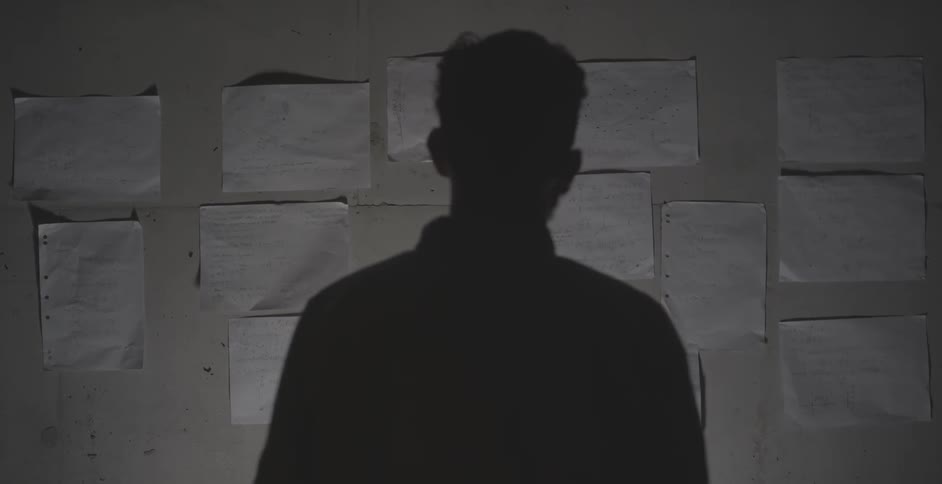 Man looks at papers taped to a wall