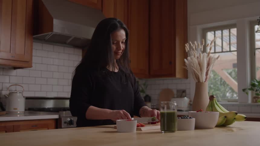 Woman prepares fruit in a kitchen lit by natural light
