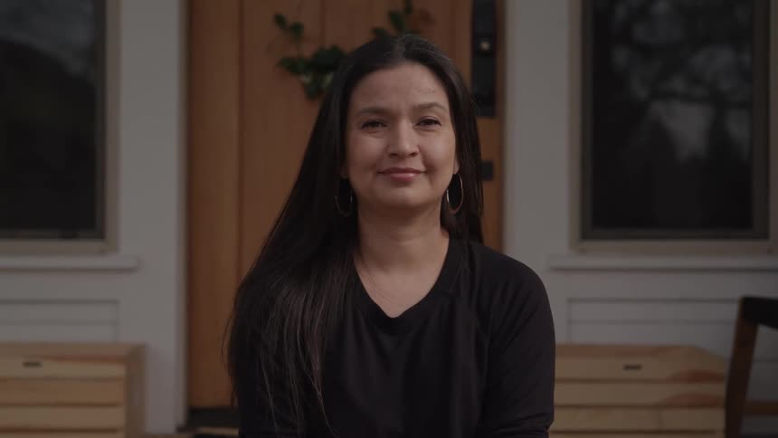 A woman with a sad look turns her head and cracks a smile