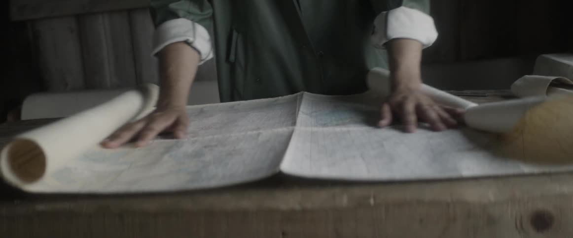 Man unrolling a map on a table