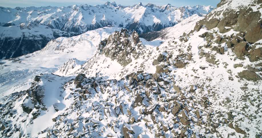 Snow covers craggy mountainous terrain on a cloudy winter day
