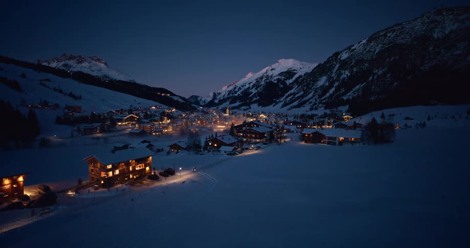 Alpine village illuminated at night between snowcovered mountains