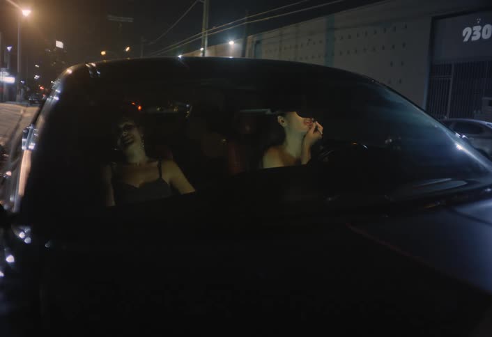 The woman is putting on makeup in the car at night