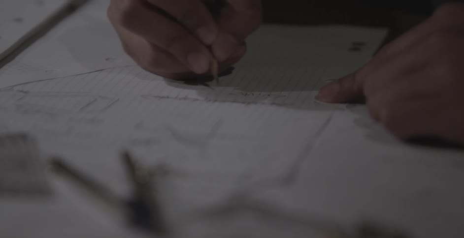 A man is writing with a pencil on graph paper