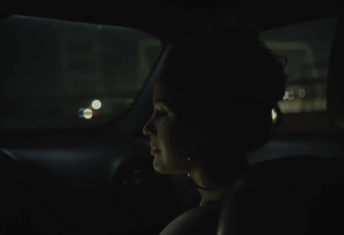 Female passenger smiles while riding in a car traveling through the city at night