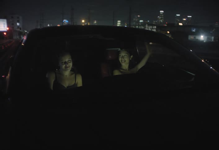 Two women drive through the illuminated city at night