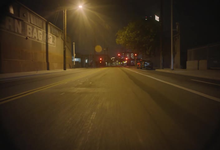 The surface of an asphalt street at night with some lampposts illuminating the yellowish environment