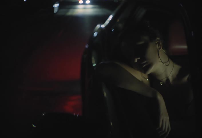 A young woman sitting in the back seat of a car during a city ride looks tired and is about to fall asleep