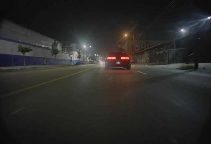 Tail lights glow in the darkness as a car takes off down the road