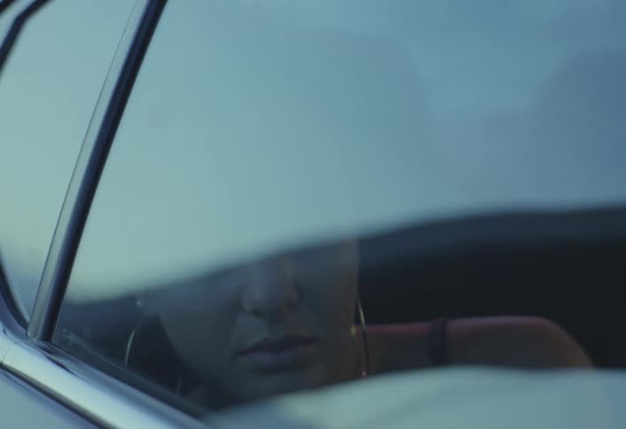 Woman sleeps leaning against the window of a moving car