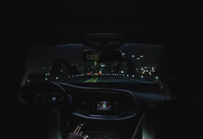 Two young women in a car at night in a metropolitan area talking and laughing while one of them drives