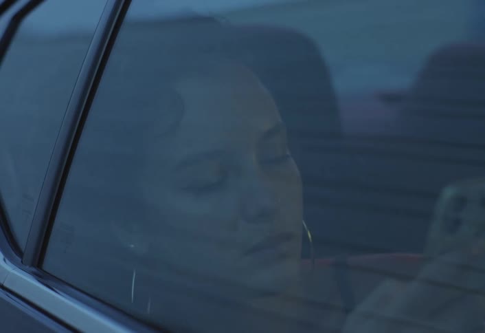 The woman looks at her phone while riding in the car