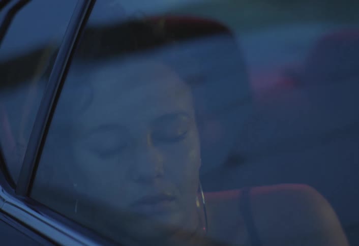 Woman gazes thoughtfully out the car window at dusk