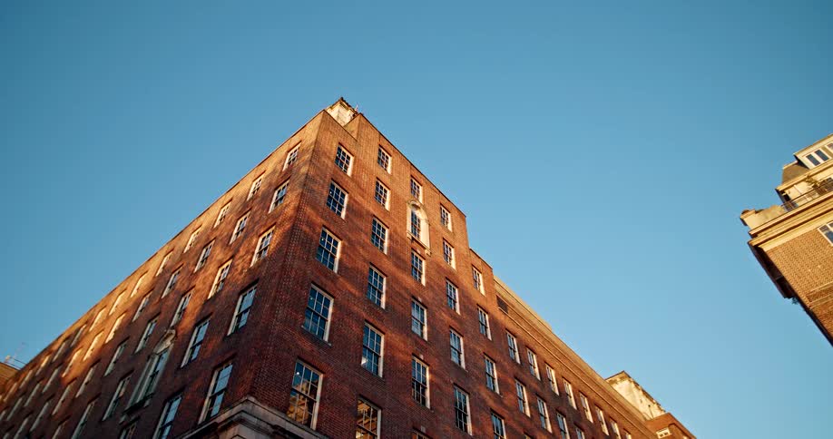 Tall red brick building surrounded by other buildings on a metropolitan area outdoors during dusk or dawn